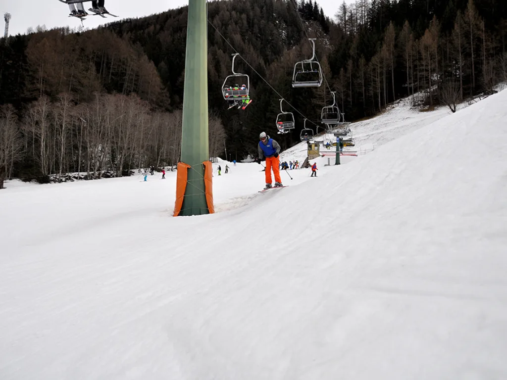 Skifahrer in roter Hose fährt an der Liftstütze vorbei.